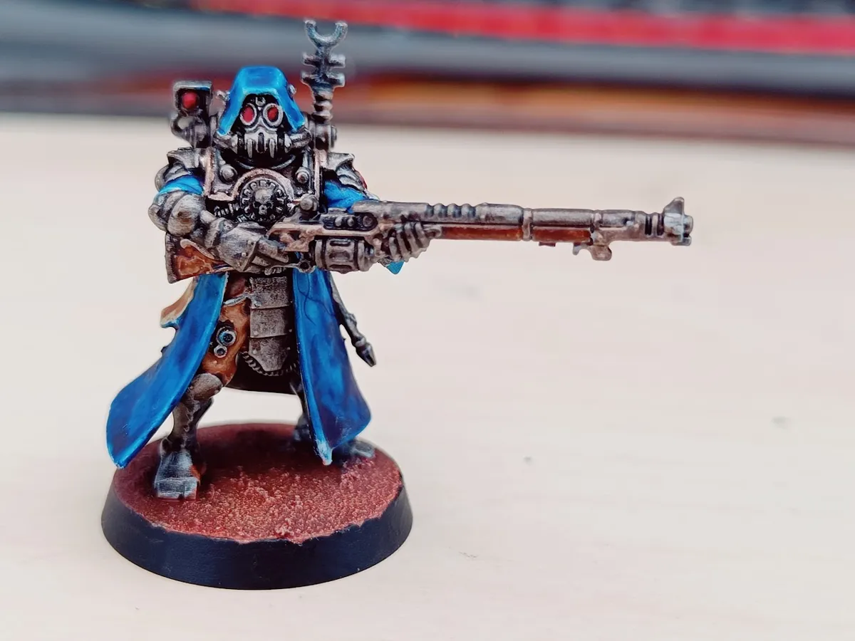 A Skitarii Ranger in a blue cloak aiming a long rifle